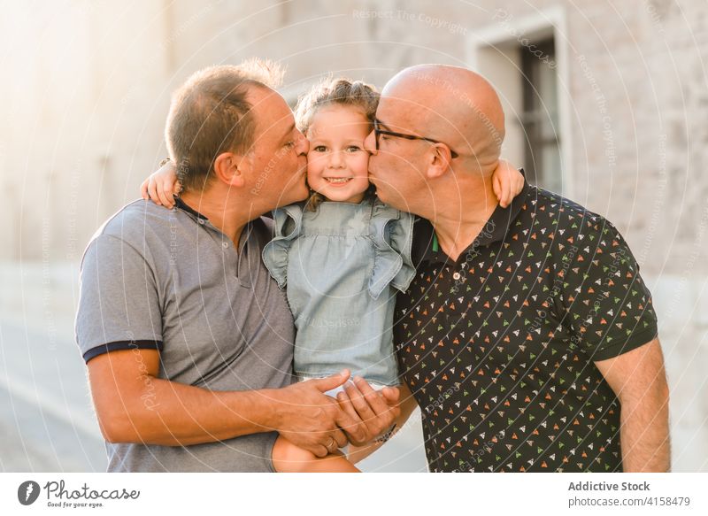 Delighted LGBT family walking on street lgbt together father men gay couple child entertain city passage weekend summer kid happy joy cheerful cute girl