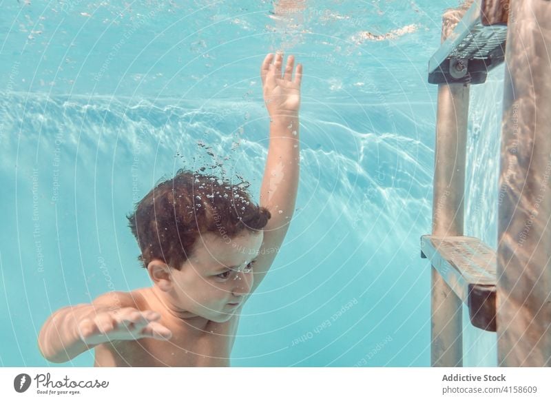 Cheerful boy in swimming pool kid dive playful delight childhood vacation summer having fun water recreation joy aqua cheerful swimsuit clear holiday pleasure