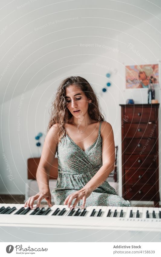 Woman playing piano in living room music musician woman rehearsal talent skill creative melody ethnic female modern apartment song perform sound entertain sit