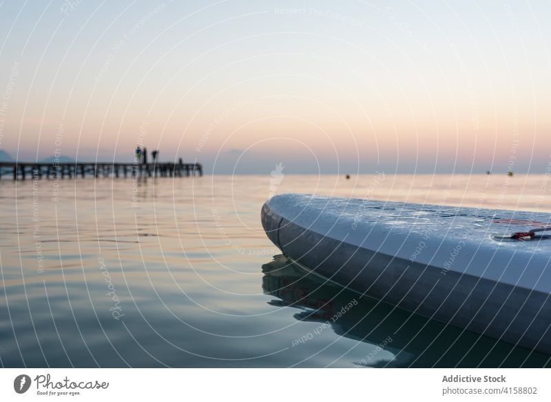 Paddleboard against spectacular sunset sky paddleboard surfer equipment sup board row sea surfboard summer sporty calm water sundown twilight dusk nobody