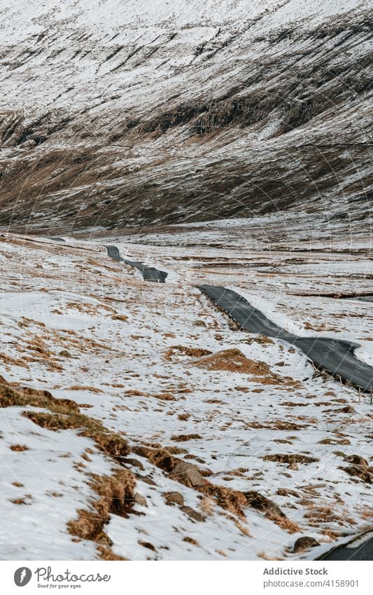 Road in mountains on Faroe Islands asphalt road snow landscape empty nature winter cold roadway cloudy hill scenery trip weather season overcast range ridge