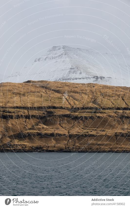 Rocky cliff near sea on Faroe Islands rock seascape winter snow season cold steep terrain faroe islands rocky scenery majestic coast shore water sky calm