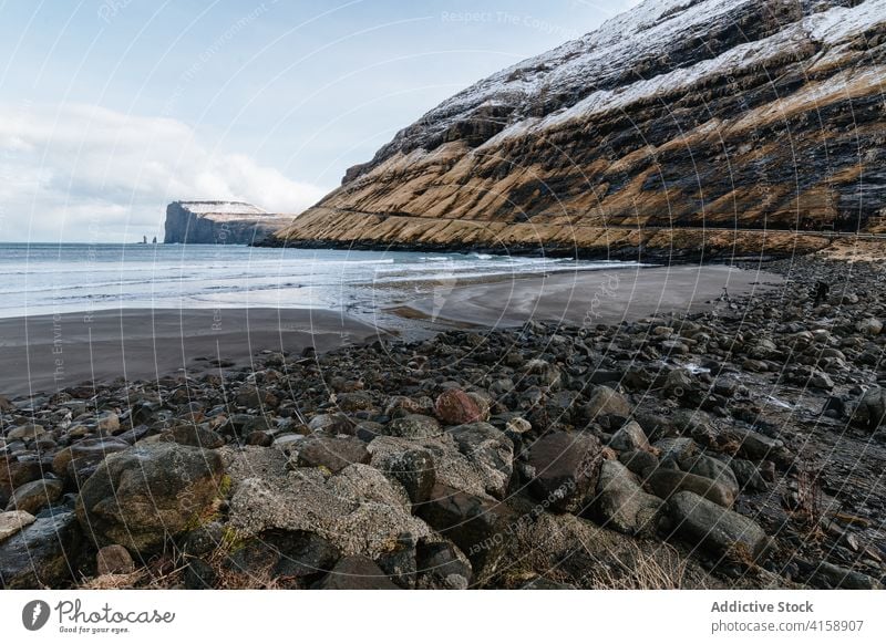 Rocky cliff near sea on Faroe Islands rock seascape winter snow season cold steep terrain faroe islands rocky scenery majestic coast shore water sky calm