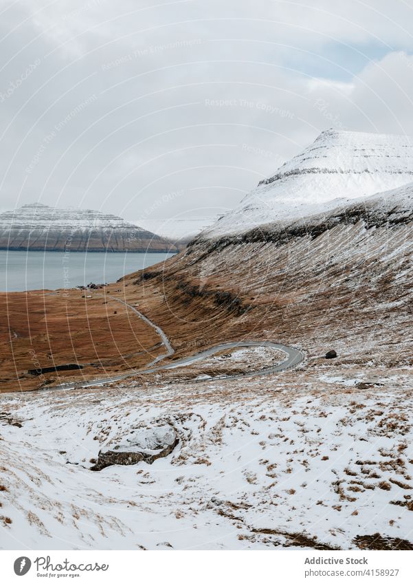 Road in mountains on Faroe Islands asphalt road snow landscape empty nature winter cold roadway cloudy hill scenery trip weather season overcast range ridge