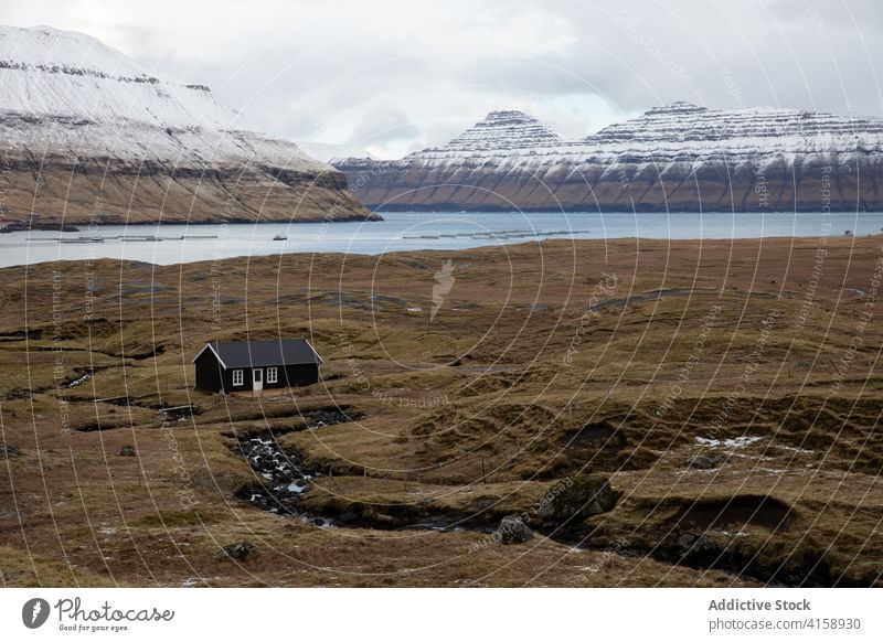 Small cabin wooden house in mountains on Faroe Islands village settlement winter snow river season cold residential faroe islands scenery breathtaking scenic