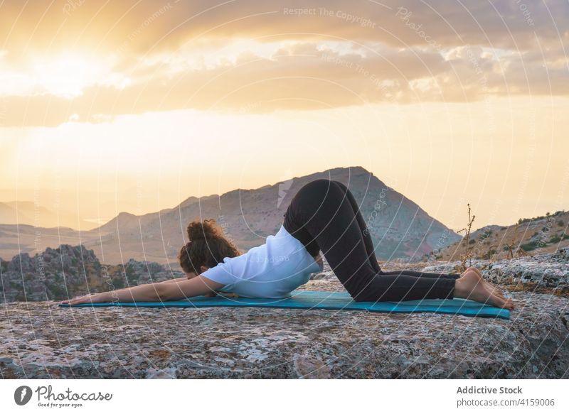 Woman stretching body in yoga position in nature woman asana extended puppy pose uttana shishosana mountain flexible practice rock wellness harmony balance