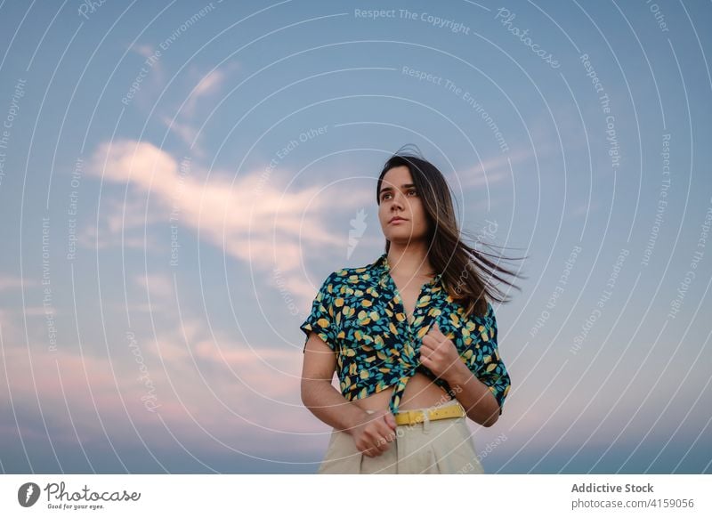 Dreamy woman under cloudy sky at sunset dreamy blue sky ornament style harmony idyllic appearance trendy apparel charming feminine stylish wear enjoy