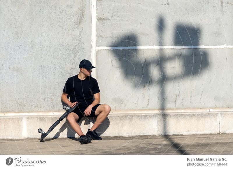 Teenager dressed in black and cap skateboarding in industrial zone teenager parking lot abandoned layered haircut solo rooftop seriousness clear sky shorts