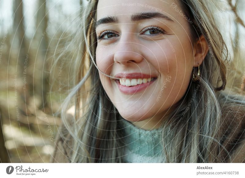 Beautiful blonde girl stands in front of a forest and smiles at the camera Girl Smiling joyfully Landscape out Blonde Joy Exterior shot Face Young woman pretty