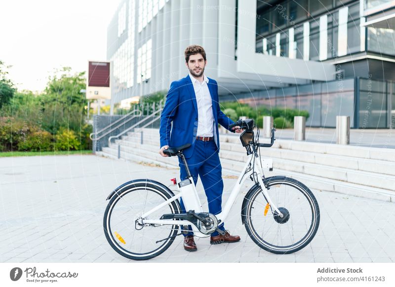 Stylish man in suit walking on pavement with electric bike stylish apparel fashion commute street masculine formal wear style modern creative design vehicle