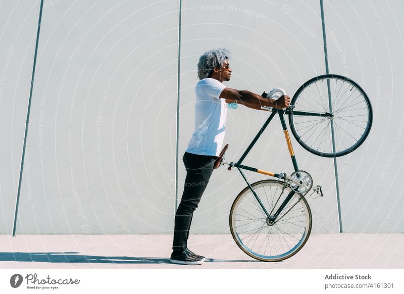 Black and afro man taking the bike and carrying it on a gray bac carrying the bike black cyclist rider black rider climbing bike city bike bycicle black man