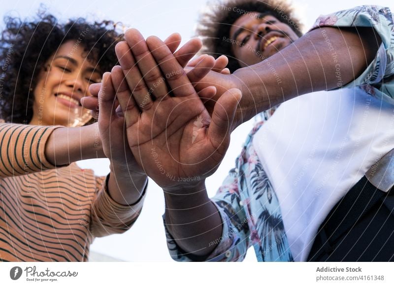 Joyful young black couple stacking hands together and smiling stack hands smile happy positive relationship joy friendship having fun optimist gesture enjoy