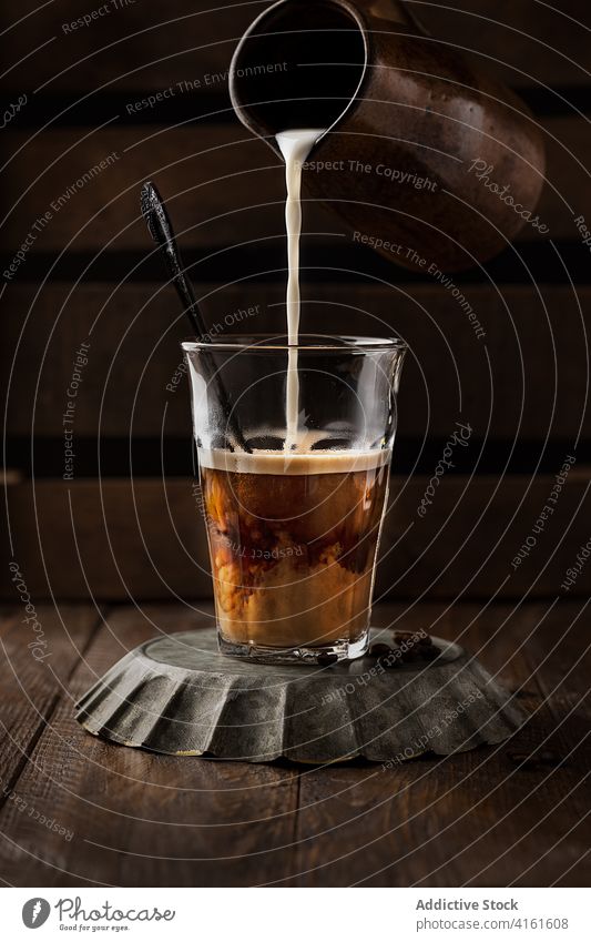 Unrecognizable person pouring milk in coffee add hot drink cafe table serve glass fresh wooden cozy beverage cafeteria aroma cup yummy brew caffeine tasty