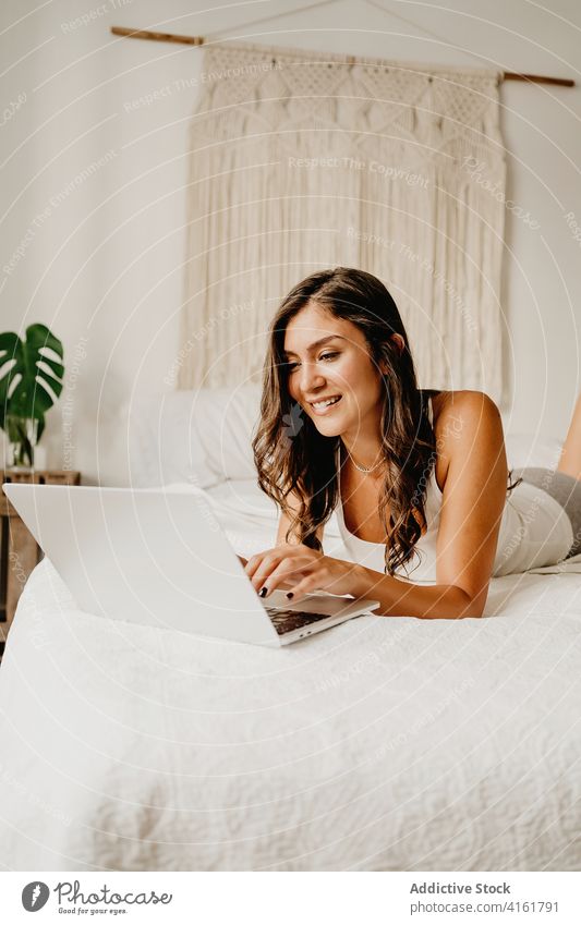 Joyful woman browsing laptop on bed morning using happy bedroom home cheerful young female device gadget internet cozy carefree chill student online delight