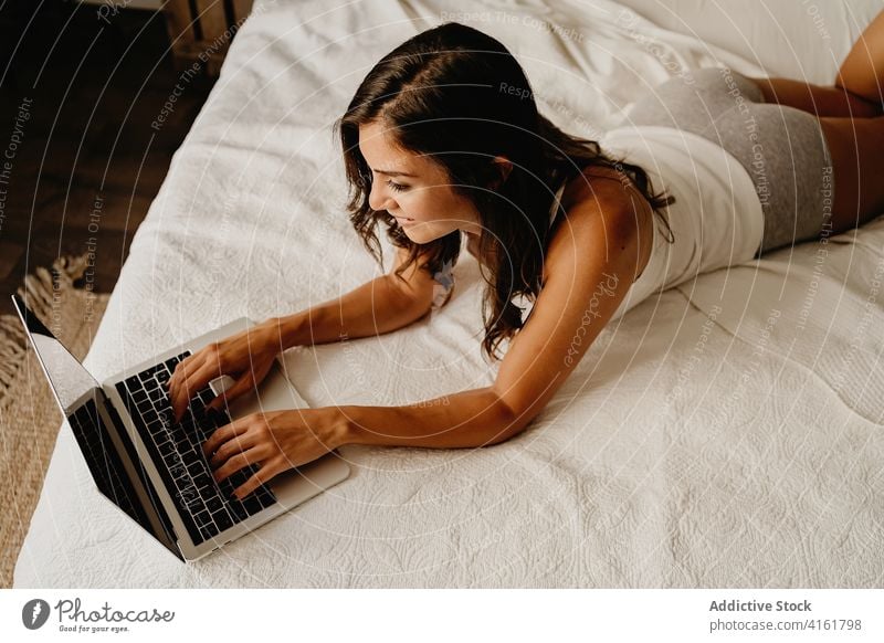 Joyful woman browsing laptop on bed morning using happy bedroom home cheerful young female device gadget internet cozy carefree chill student online delight