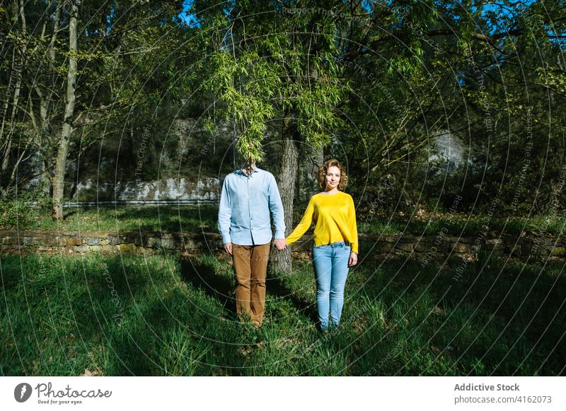 Couple standing together in park holding hands couple calm tree cover face romantic summer sunlight boyfriend girlfriend relationship creative weird fancy lawn