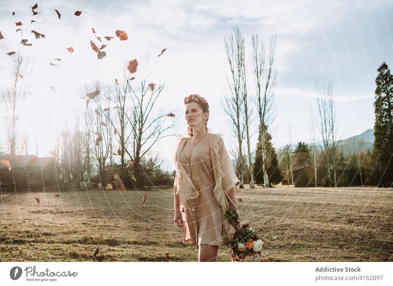 Romantic woman with bouquet walking in autumn countryside romantic bride boho dreamy style pensive young bohemian garment wreath leaf wind nature flower season