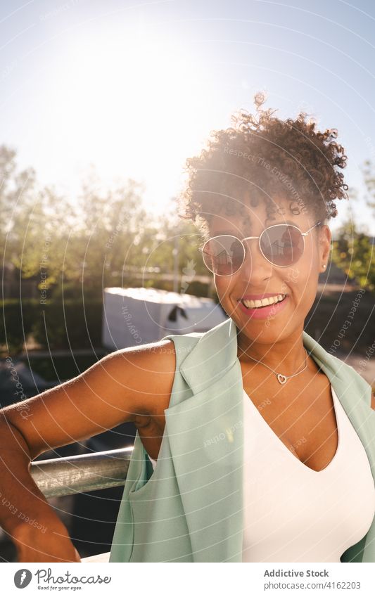 Stylish ethnic woman in sunglasses standing near fence style trendy happy summer afro smile cheerful young female african american black positive relax casual