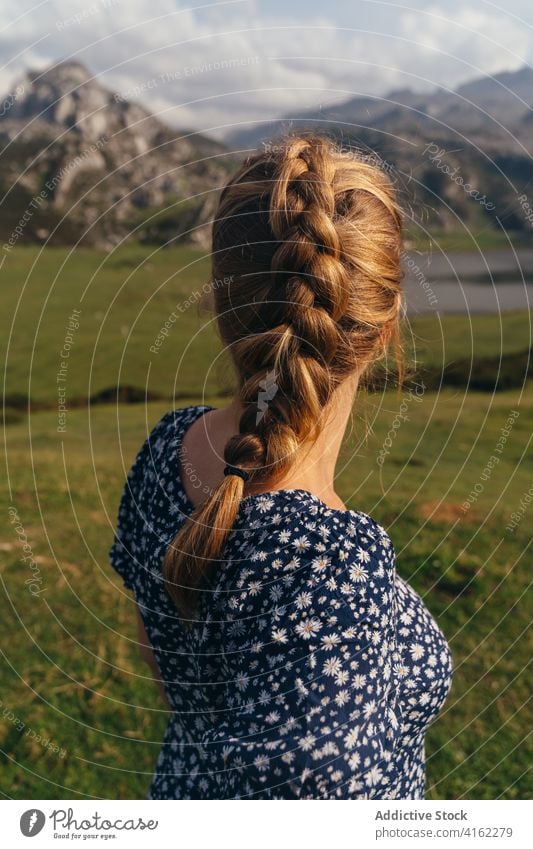 Faceless woman resting on stone against spectacular mountainous valley highland magnificent admire terrain pond landscape range lake scenery hillside nature