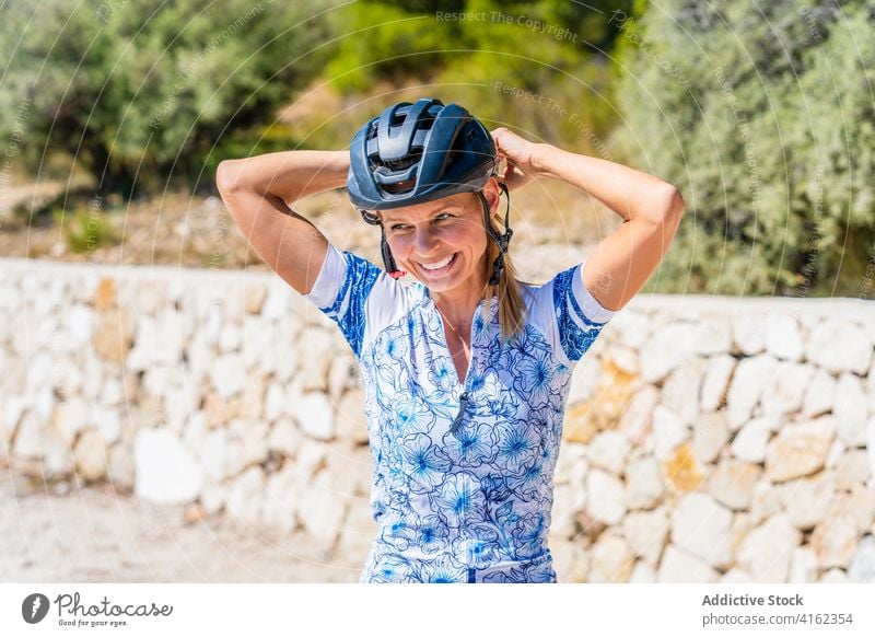 Cheerful woman putting on bike helmet cyclist active happy prepare sporty bicyclist protect cheerful ride young female laugh safety lifestyle smile put on