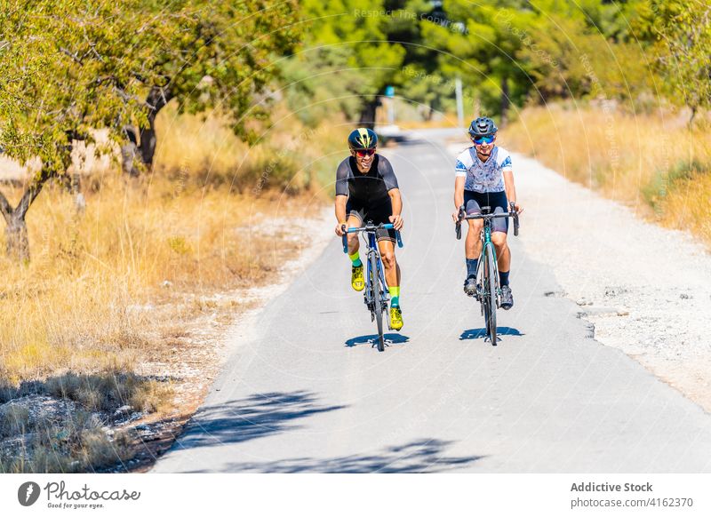 Cyclists riding bikes in countryside cyclist ride road couple bicycle active together friend lifestyle sport activity healthy summer viaduct archway roadway