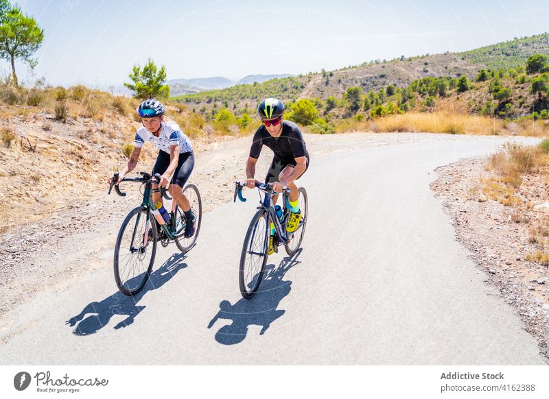 Cyclists riding bikes in countryside cyclist ride road couple bicycle active together friend lifestyle sport activity healthy summer viaduct archway roadway