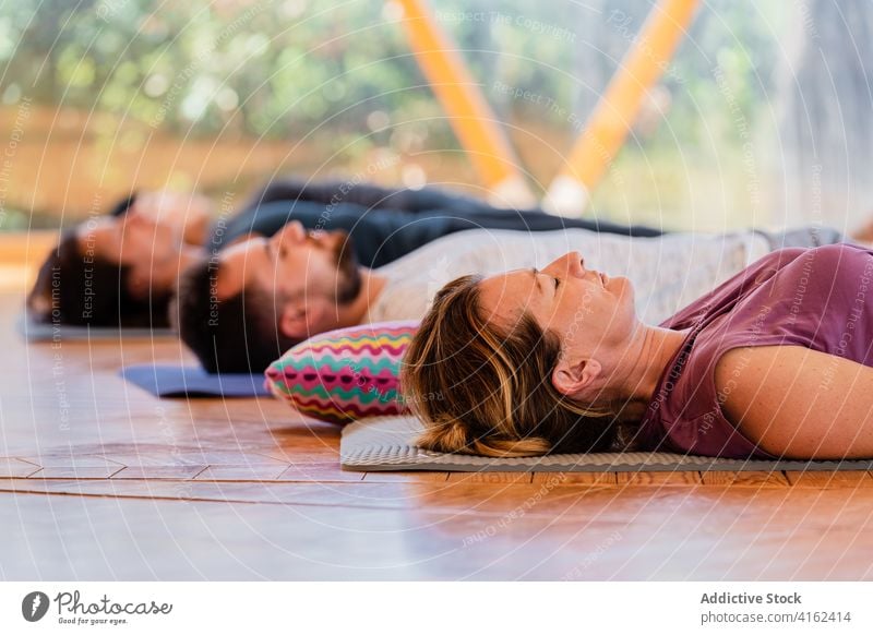 People in Shavasana pose on yoga mats people shavasana relax eyes closed meditate zen peaceful harmony class lying floor reflective together spirit