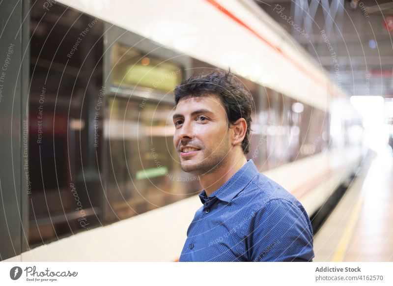 Young man with blue shirt waiting at train station smartphone lifestyle entrepreneur business public businessman success transportation urban caucasian modern