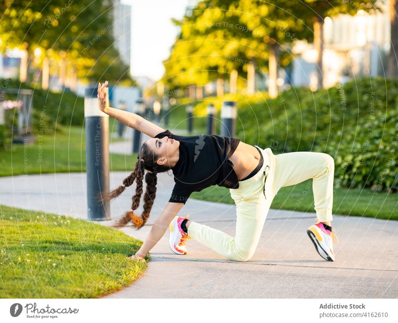 Flexible young woman dancing in park dance pathway active ballerina trendy flexible city move energy cool hobby female style outfit hairstyle sneakers modern