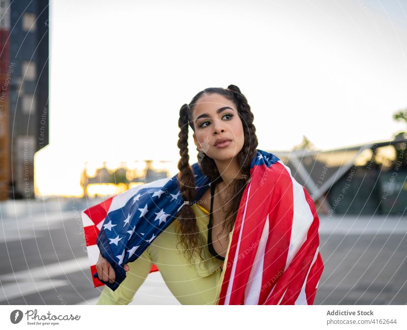 Sensual young ethnic raising US flag near skyscraper woman confident american sensual trendy happy patriot celebrate independence day national female city urban