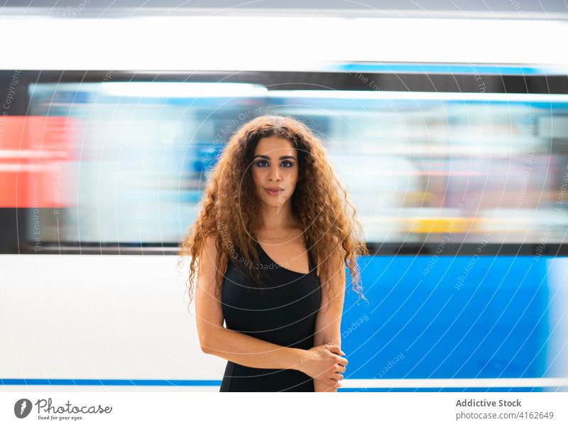 Content young ethnic female passenger in metro station woman grace confident subway underground content portrait smile joy wait long hair curly hair feminine