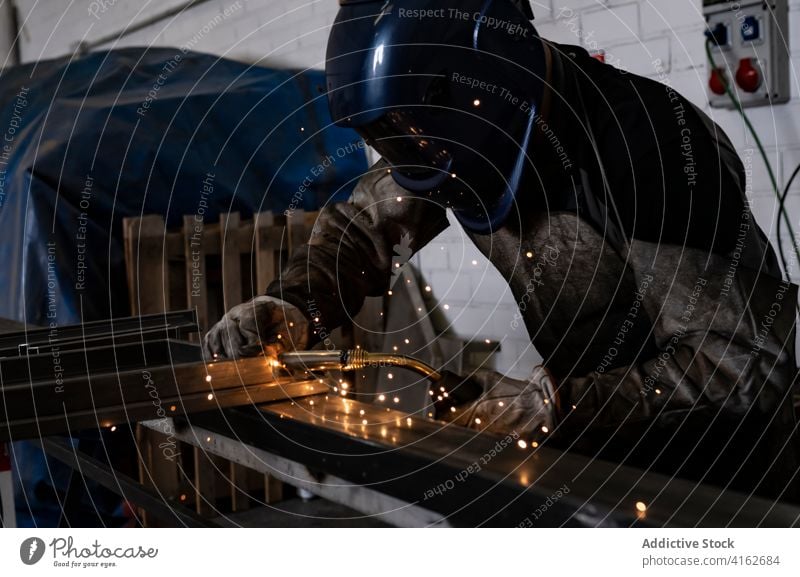 Professional welder in protective helmet in workshop metal man machine dark spark light male worker occupation professional tool industry job equipment labor