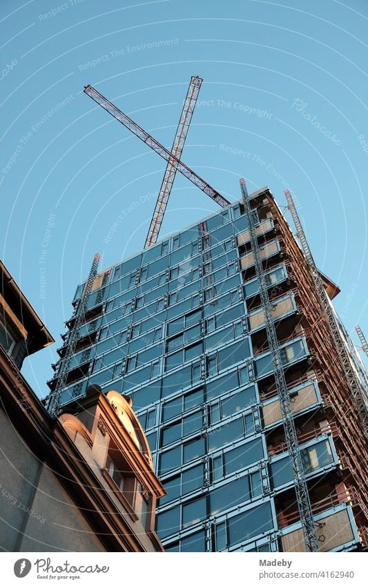 Mansard or dormer of an old villa in front of a high-rise building with glass facade and construction cranes in the West End of Frankfurt am Main in Hesse