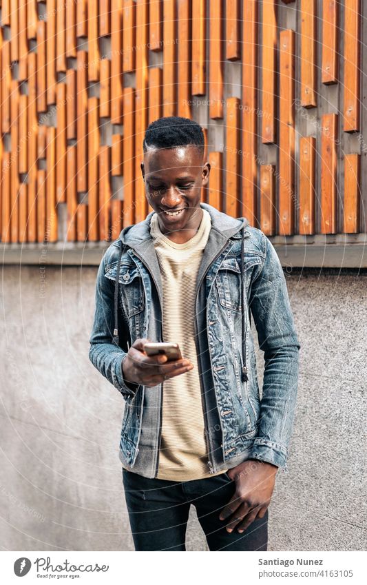 Portrait Of Young African American Man portrait african american using phone street typing mobile phone front view looking phone black ethnic afro cellphone