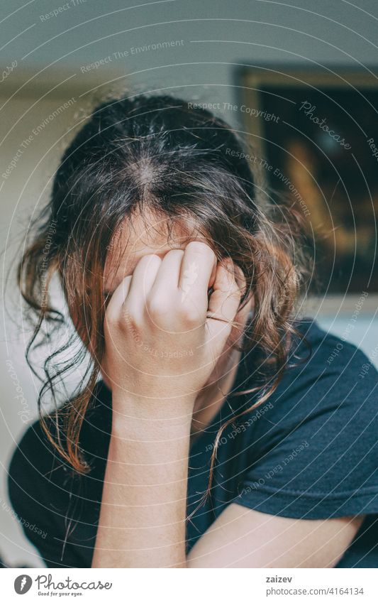 Girl with hand on sad and disappointed face adult lifestyle woman female portrait young isolated color image home person sleepy displeased photography