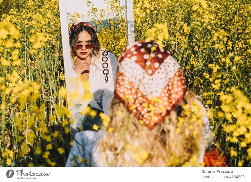 Image of a beautiful woman looking at her reflection in a mirror in a field of spring flowers Beautiful Blonde Sunglasses paradise relax scene summer summertime