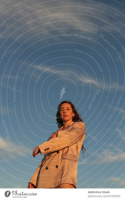 Stylish tranquil woman against blue sky style trendy model appearance serene gorgeous sensual arms raised elegant harmony grace peaceful outfit beautiful