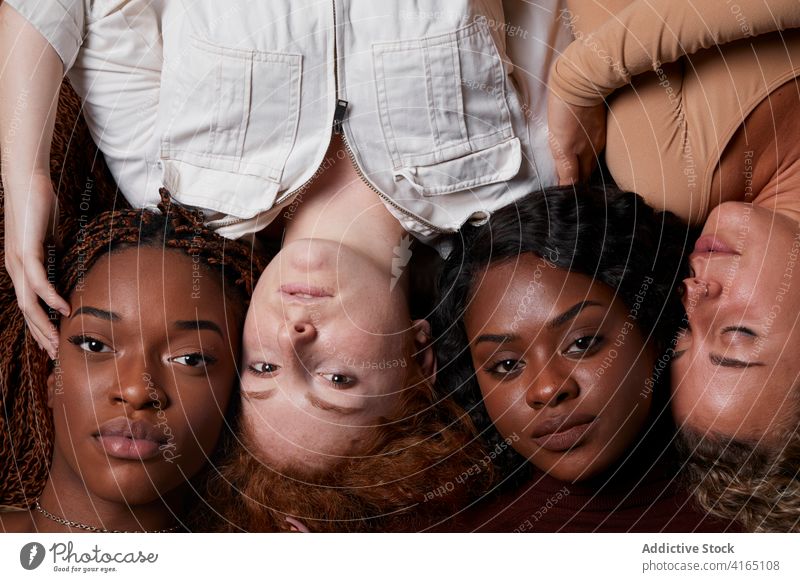 Multiracial women lying in row in studio together model pastel color outfit curly hair multiethnic multiracial diverse black african american line floor rest