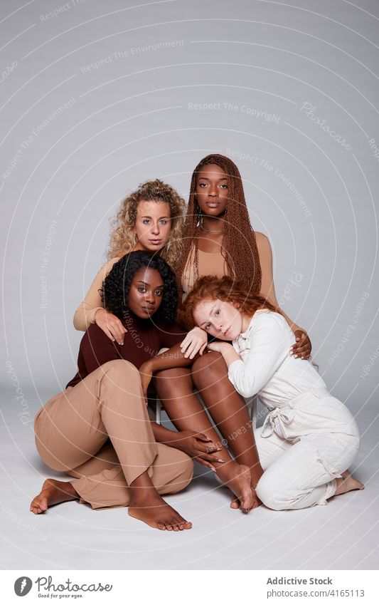 Multiethnic women gathering on gray background unity hug together friendship cuddle tender company multiethnic multiracial diverse black african american