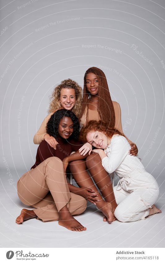 Multiethnic women gathering on gray background unity hug together friendship cuddle tender company multiethnic multiracial diverse black african american