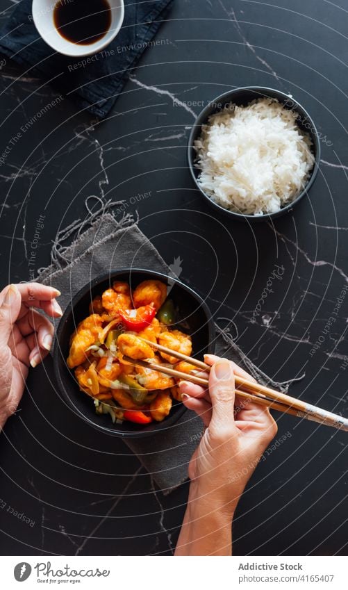 Faceless lady having dinner with chopsticks in Asian restaurant woman eat chicken dish asian food appetizing delicious meal rice soy sauce tradition