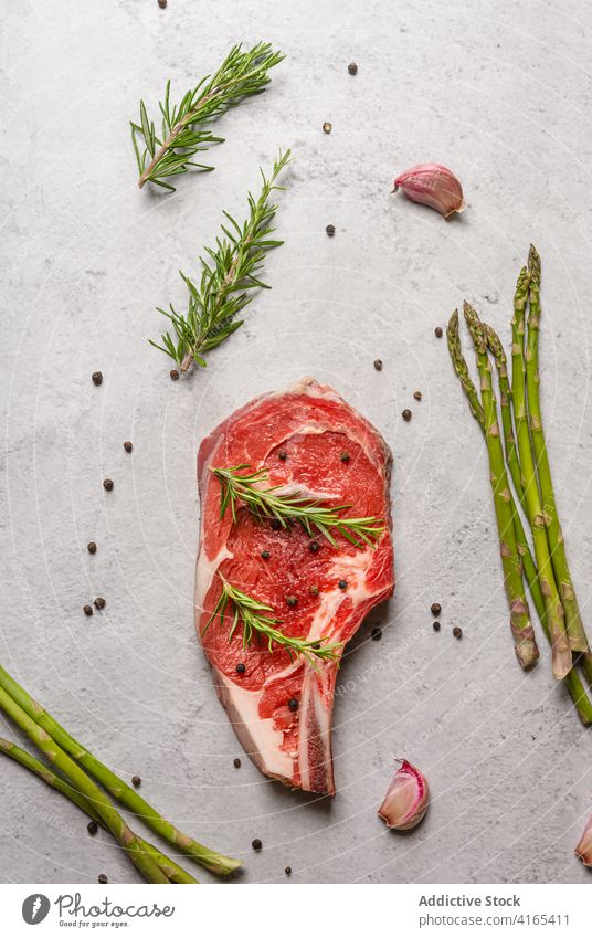 Raw beef steak with herbs on table raw bone t bone rosemary garnish meat pepper black kitchen cook food cuisine delicious dish spice gourmet fresh recipe sprig