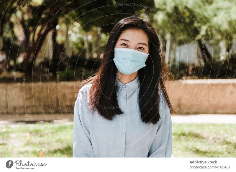 Young Asian woman chilling in park during coronavirus positive elegant new normal relax enjoy calm formal fashion nature female young ethnic asian chinese