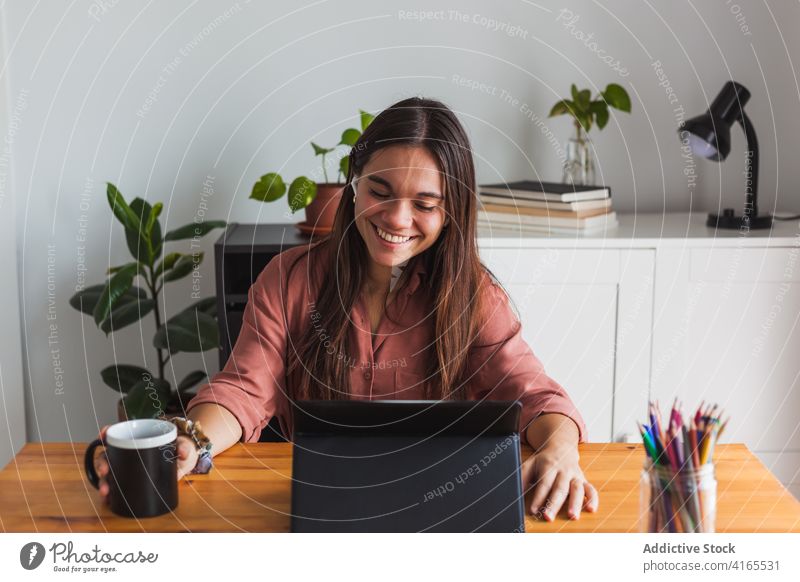 Smiling woman in earbuds typing on laptop at home workplace netbook happy browsing toothy smile satisfied using cheerful smart surfing gadget contemporary