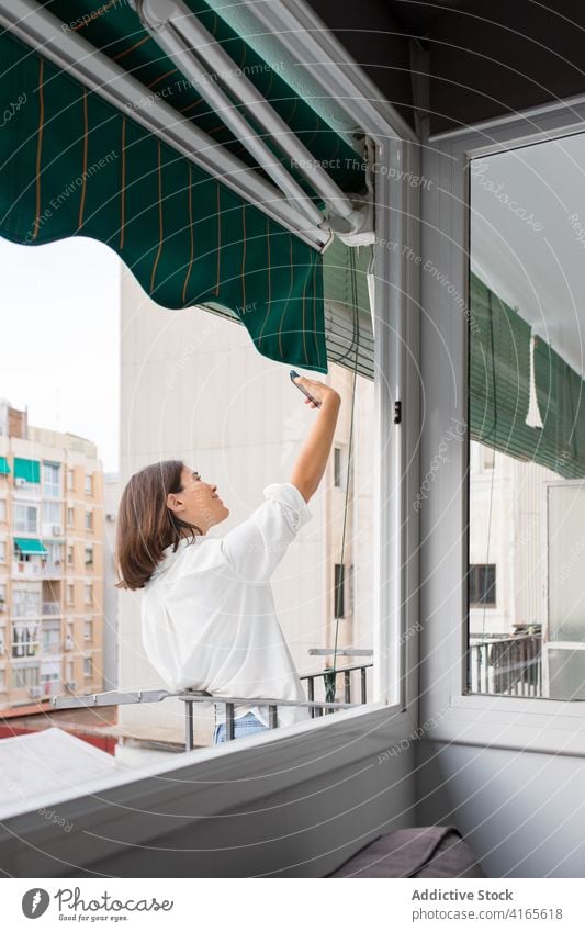 Young lady taking selfie on smartphone on balcony woman home relax photo connection mobile female young picture casual brunette railing daytime device gadget