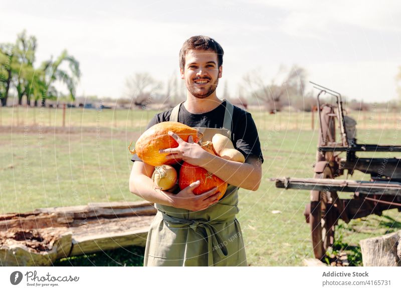 Smiling farmer with pumpkins in countryside harvest man joy squash vegetable village season male orange delight positive optimist smile cheerful happy garden