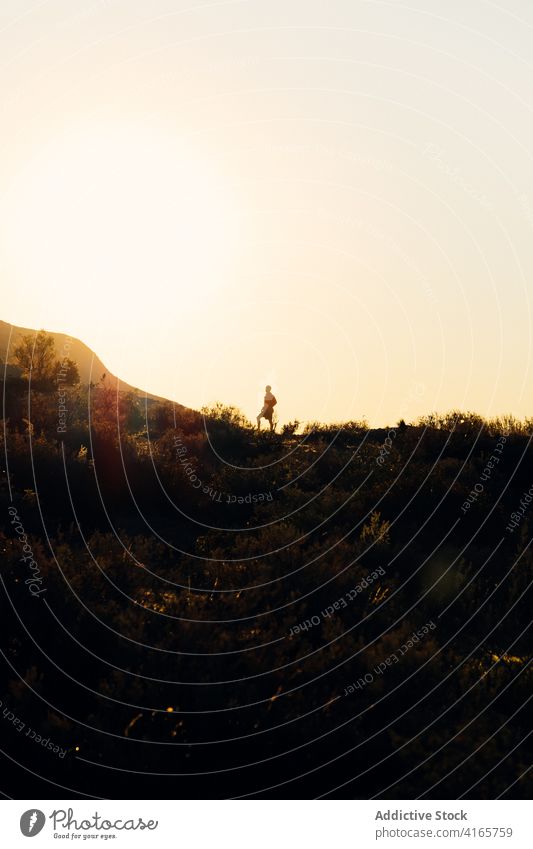 Anonymous person running on hill at sundown mountain slope workout sunset athlete climb training silhouette exercise healthy sport endurance wellness fit nature