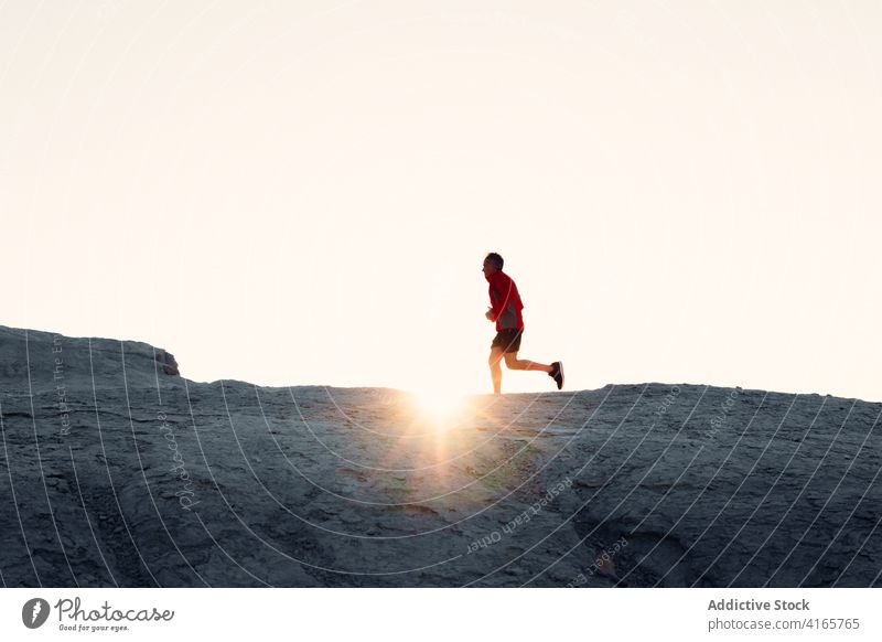 Anonymous person running on hill at sundown mountain slope workout sunset athlete climb training silhouette exercise healthy sport endurance wellness fit nature