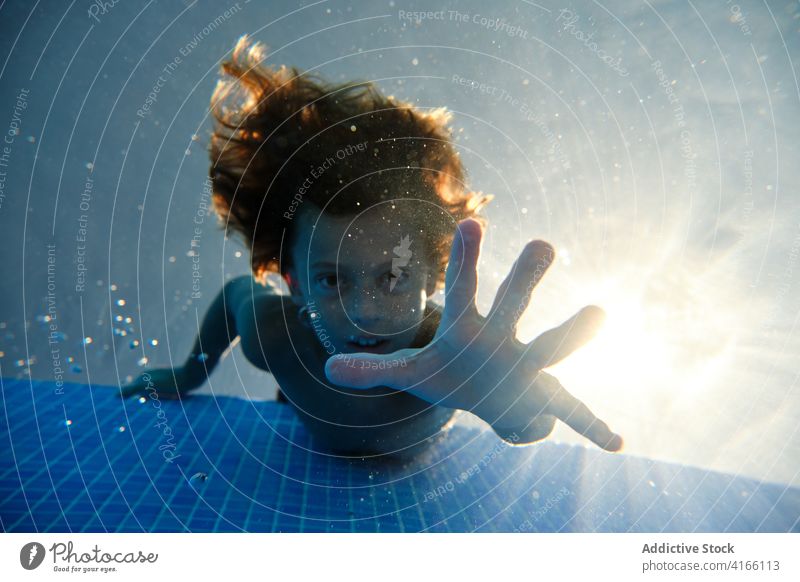 Joyful boy diving into pool water teenage dive bubble cheerful underwater activity smile fun carefree playful splash aqua active resort enjoy swim relax laugh