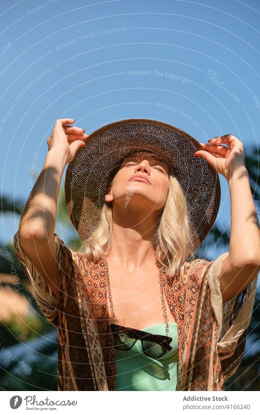 Serene traveler resting in sunlight against blue sky woman resort tourist blond vacation idyllic freedom harmony eyes closed female summer relax peaceful